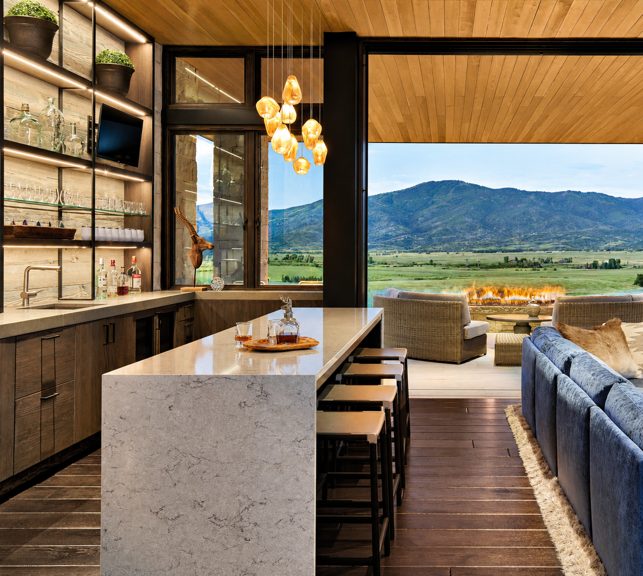 Luxury open-concept kitchen and living room with waterfall quartz island, custom wood cabinetry, pendant lighting, mountain views, and modern indoor-outdoor design.
